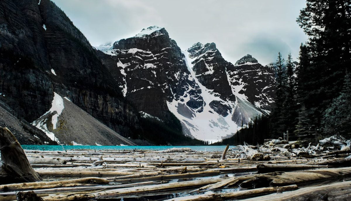 landscape of a snowy black mountain cliff near turquoise water